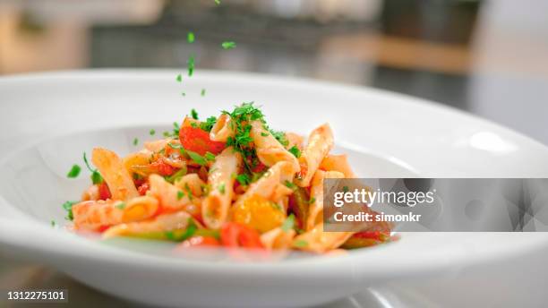 garnishing pasta with coriander herb - penne stock pictures, royalty-free photos & images