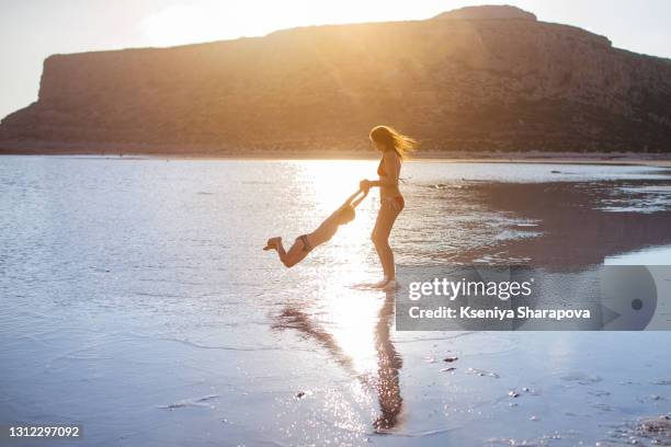 mom turns with her son in the water during sunset.beauty of balos beach and paradise island in crete, greece-stock photo - balonnen stock-fotos und bilder