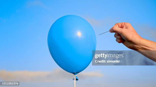 man popping blue balloon with pin - balloon burst stock pictures, royalty-free photos & images