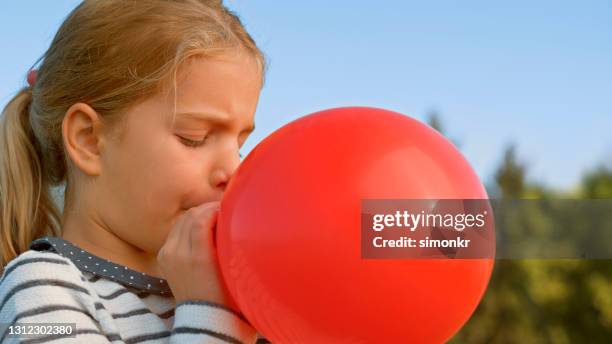 girl blowing balloon outdoors - blowing balloon stock pictures, royalty-free photos & images