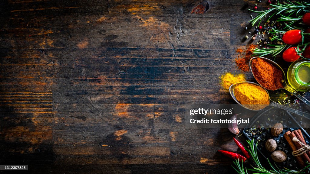 Colored spices and herbs border on dark table