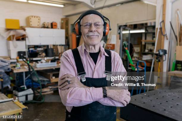 mature workshop owner wearing protective ear guards - wood worker posing stock-fotos und bilder