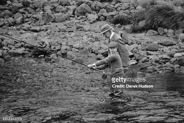 Prince Edward pictured wearing waders and a tweed cap being taught fly fishing with a ghillie in the River Dee in 1975