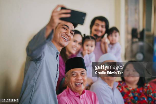 malaysian malay family taking selfie photo looking at camera waving at home celebrating hari raya - great grandfather stock pictures, royalty-free photos & images