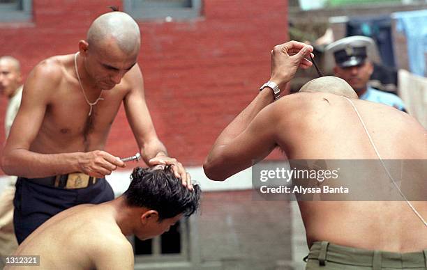 Police officers shave each other''s heads June 3, 2001 in the Nepalese capital of Kathmandu as a sign of respect for their king and other members of...