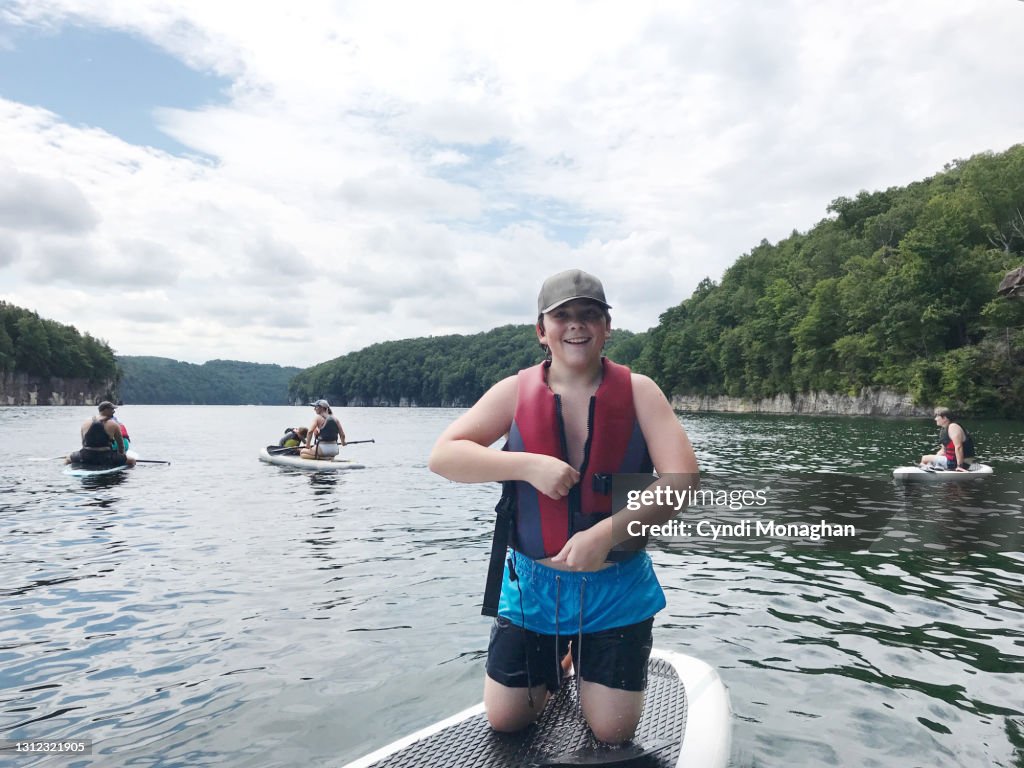Smiling Boy Paddleboarding with His Family