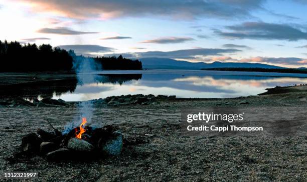 camp fire on lakeside beach at lake richardson in western maine - orilla del lago fotografías e imágenes de stock