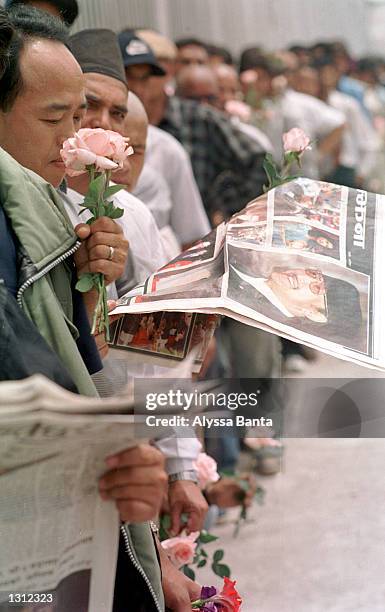 Man reads the newspaper featuring photographs of the Nepalese royal family while he waits in line with others to sign the book of condolence at the...