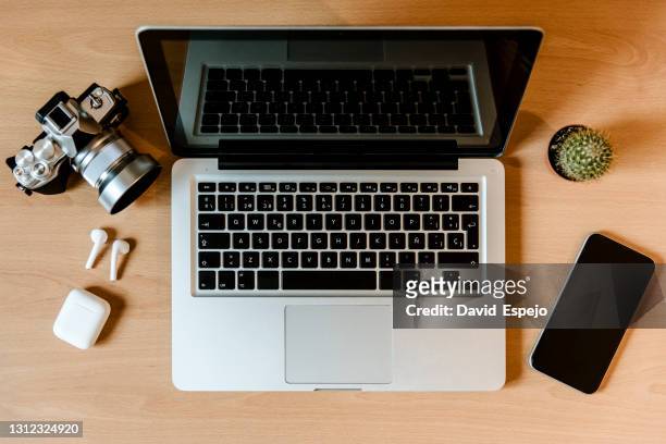 still life of laptop with camera, smartphone and headphones on desk. modern devices on the desktop in the office. - phone still life stock pictures, royalty-free photos & images