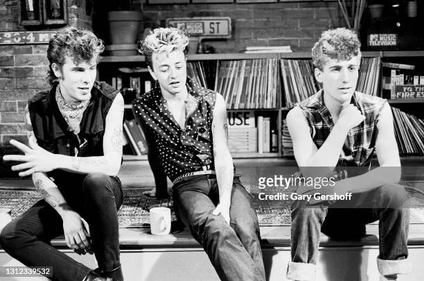 View of, from left, Rockabilly musicians 'Slim' Jim Phantom , Brian Setzer, and Lee Rocker , all of the band the Stray Cats, as they sit on a low...