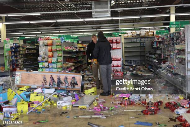 Workers survey damage to a Dollar Tree store in a strip mall near the Brooklyn Center police station after it was vandalized and looted during the...