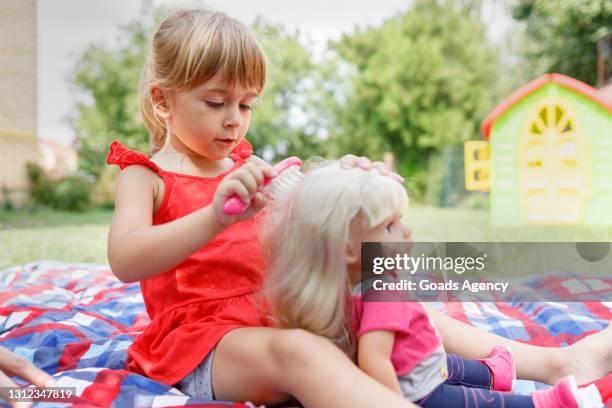 ragazza che spazzola i capelli della sua bambola - doll foto e immagini stock