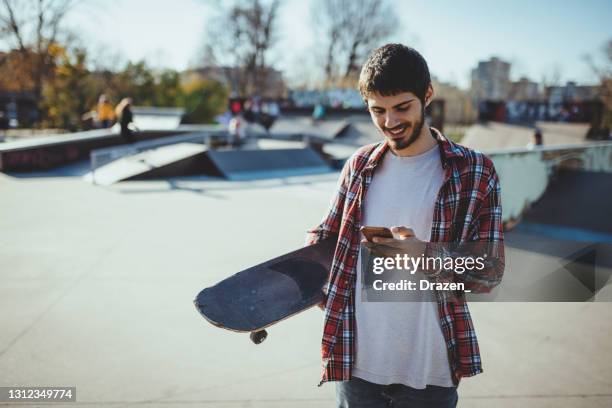 skateboarder texting friends - man skating stock pictures, royalty-free photos & images