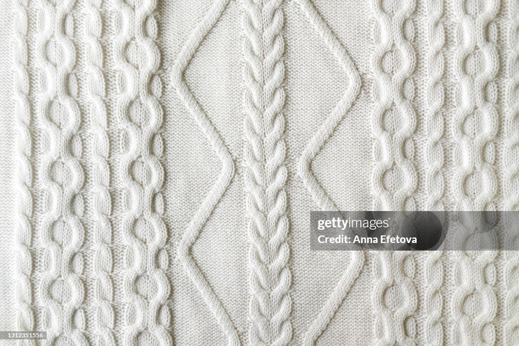 Texture of smooth knitted white sweater with pattern. Flat lay style, close-up.