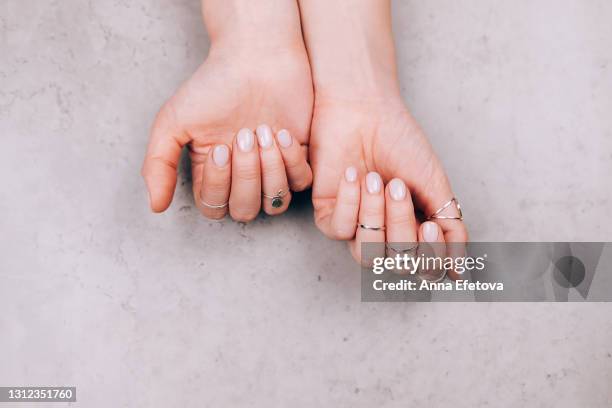 woman hands with nude pink manicure and with many various silver rings on fingers on concrete gray background. concept of trendy boho style. flat lay style with copy space - fingernail stock pictures, royalty-free photos & images