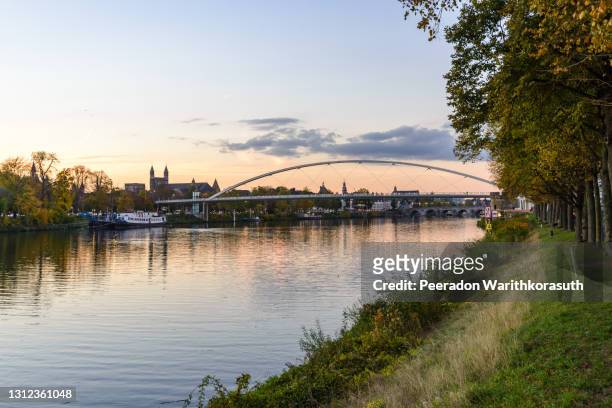 outdoor scenery on riverside of meuse river and hoge brug, modern pedestrian bridge, during sunset time and dramatic twilight sky in maastricht, netherlands. - limburg netherlands stock pictures, royalty-free photos & images