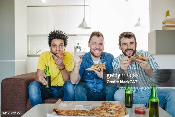 friends drinking beer, eating pizza at home and watching sports game - football cheering stock pictures, royalty-free photos & images