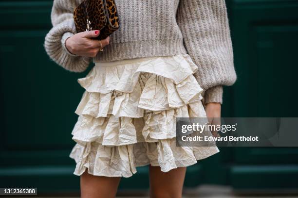 Therese Hellström @tesshell wears a gray wool oversized ribbed pullover, a brown leopard print clutch / bag, a pleated and ruffled short skirt, on...