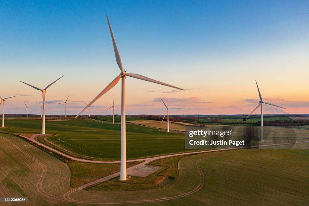 Drone view of a wind farm at sunset. Multiple wind turbines