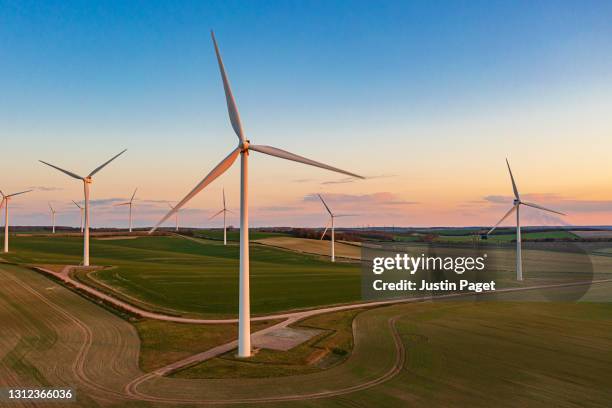 drone view of a wind farm at sunset. multiple wind turbines - wind power uk stock pictures, royalty-free photos & images