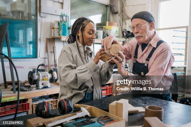 wood workshop owner assisting student with project - old man young woman stockfoto's en -beelden