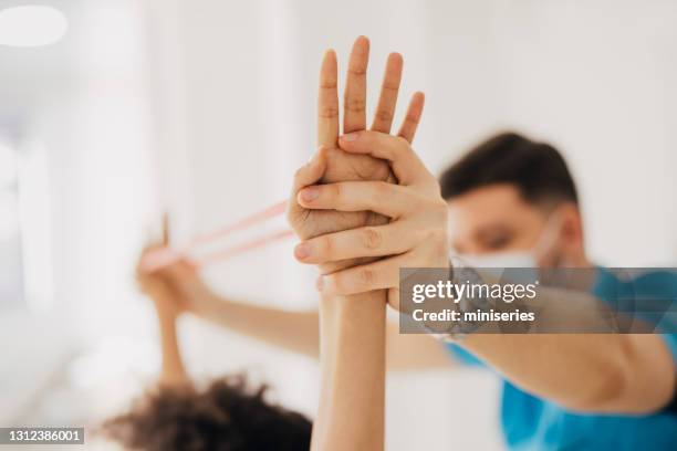 physical therapist holding patient's arms in the air - zoom in stock pictures, royalty-free photos & images
