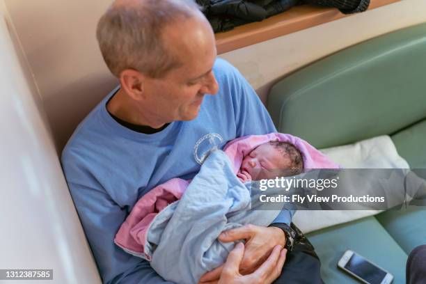 opa liebevoll halten und auf neugeborene enkelin schauen - biologische uhr stock-fotos und bilder
