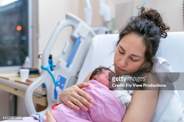 mixed race mother snuggling newborn after delivery - beginnings stock pictures, royalty-free photos & images