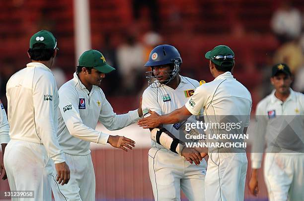 Pakistan's cricketers congratulated by Sri Lanka's batsman Kumar Sangakkara at the end of the first day of the third and final Test match between...