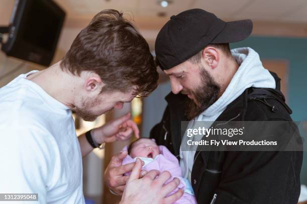 deux hommes retenant le bébé nouveau-né ensemble à l’hôpital - substitution photos et images de collection