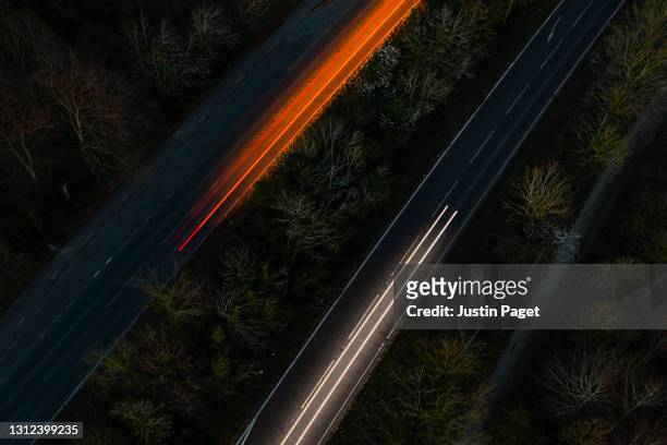 drone view of cars moving in different directions at night - car light trails stock pictures, royalty-free photos & images