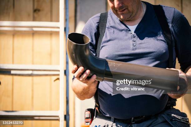roofer builder worker finishing folding a metal gutter - gutter installation stock pictures, royalty-free photos & images