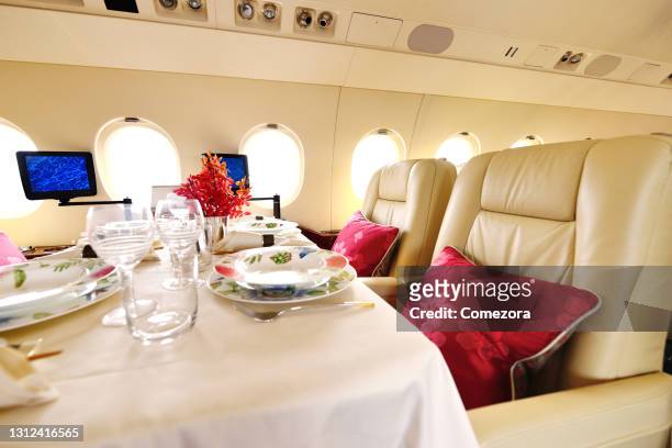 luxury seat and dining table at airplane passenger cabin - first class plane stockfoto's en -beelden