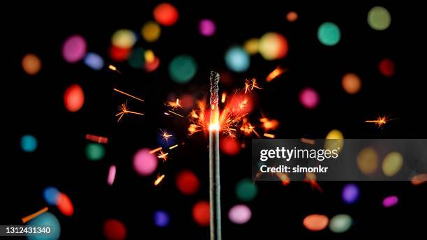 close-up of sparkler emitting sparks while confetti falling in background - diwali festival of lights stock pictures, royalty-free photos & images