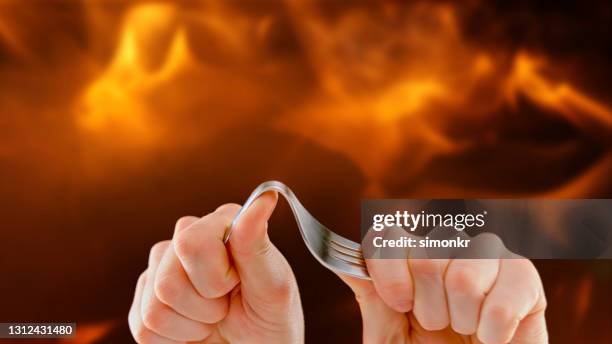 man's hands bending fork - bent spoon stock pictures, royalty-free photos & images