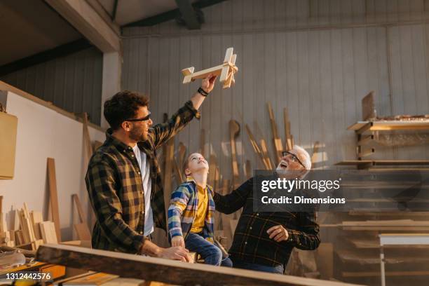 tischlerfamilie spielt mit holzspielzeug in der werkstatt - father son business europe stock-fotos und bilder