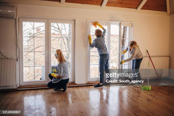mujeres limpiando ventanas en apartamento - limpieza profesional fotografías e imágenes de stock