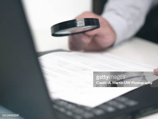 businessman reading online documents on laptop screen with magnifying glass concept for analyzing a finance agreement or legal contract - petits caractères photos et images de collection