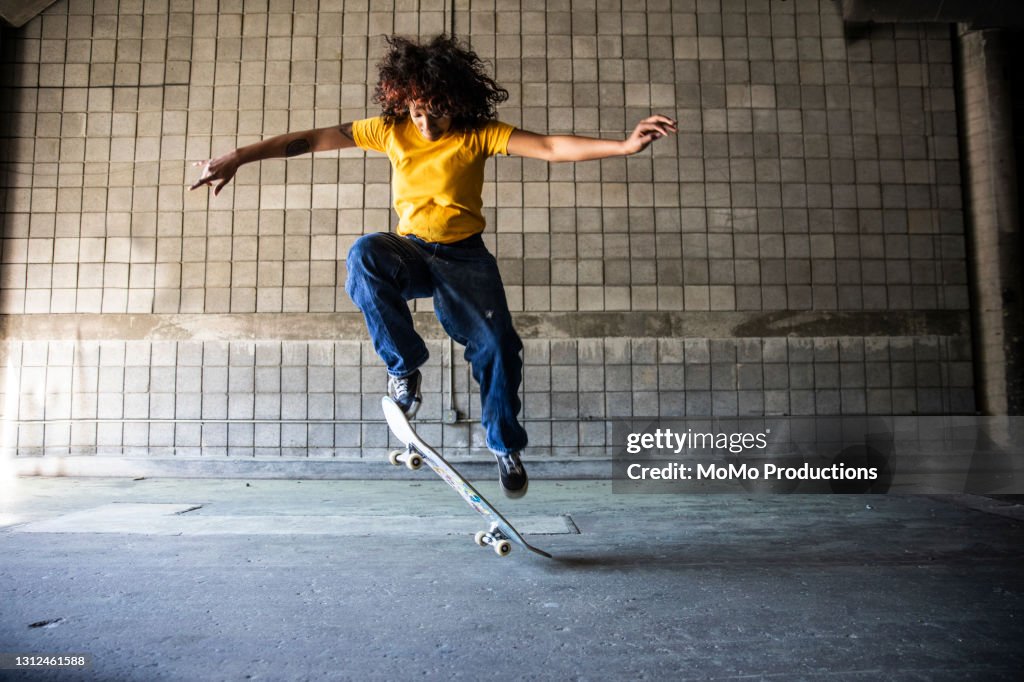 Female skateboarder performing jump in warehouse environment