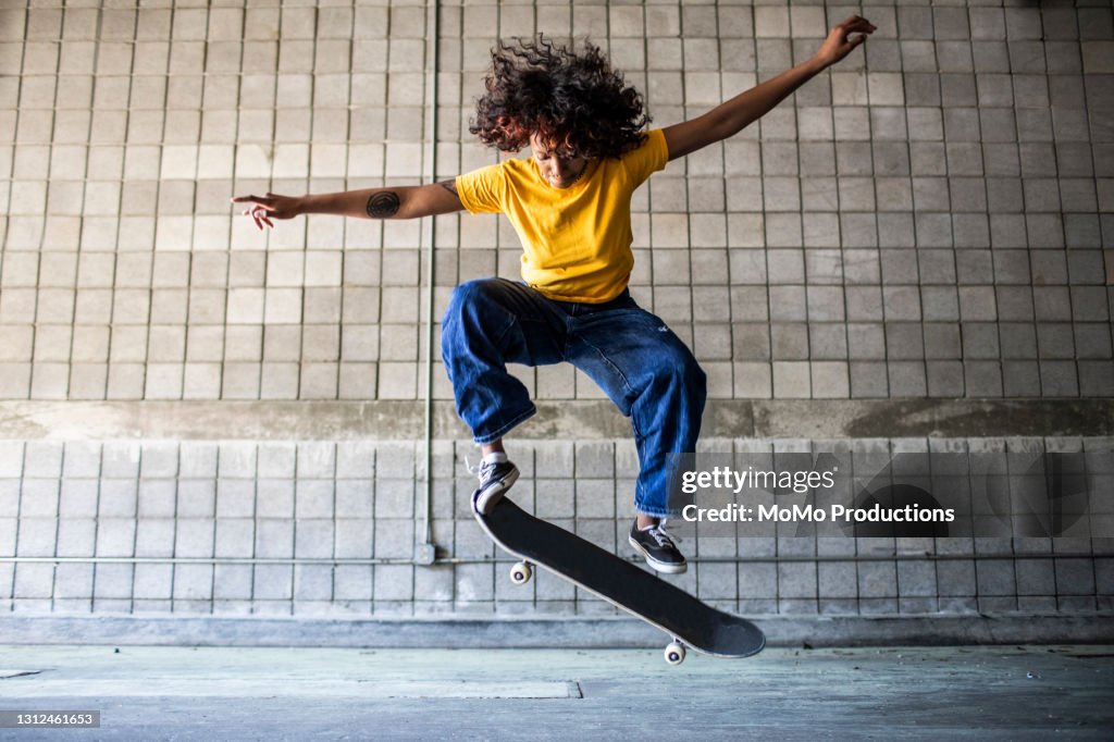 Female skateboarder performing jump in warehouse environment