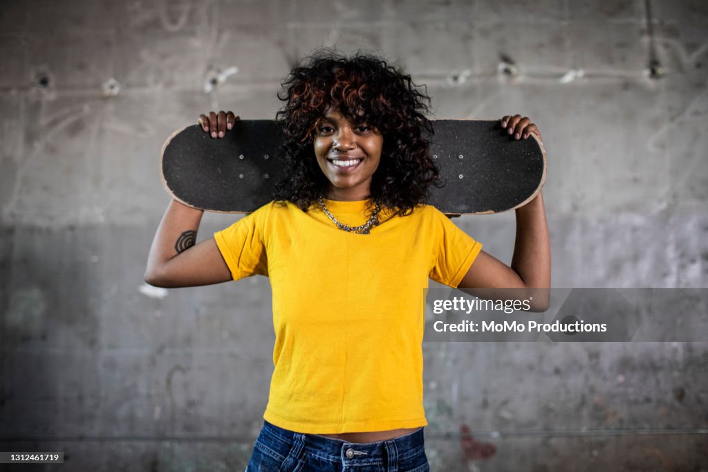 Portrait of female skateboarder in warehouse environment