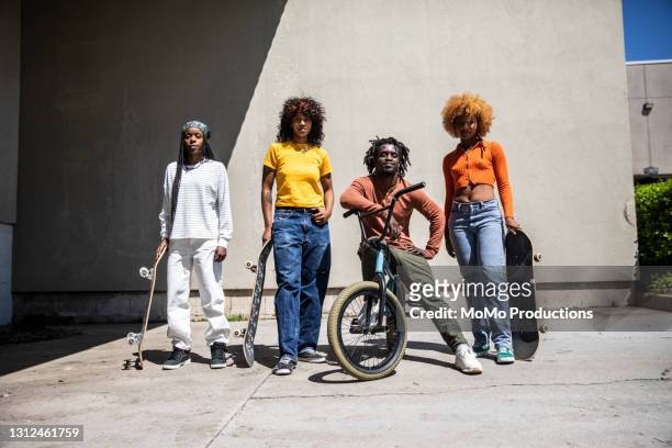 portrait of female skateboarders and bmx rider in outdoor industrial environment - sport fashion stockfoto's en -beelden