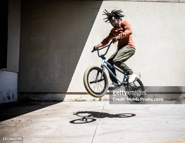 bmx rider performing jump in outdoor industrial environment - vita cittadina foto e immagini stock