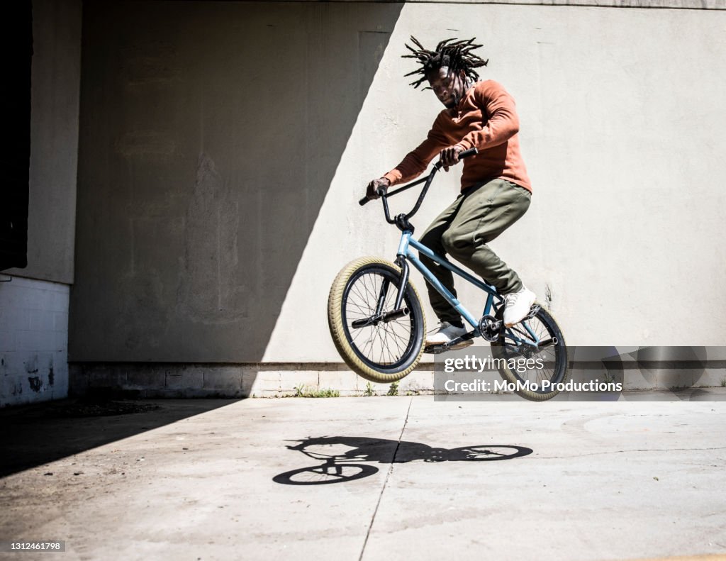 BMX rider performing jump in outdoor industrial environment