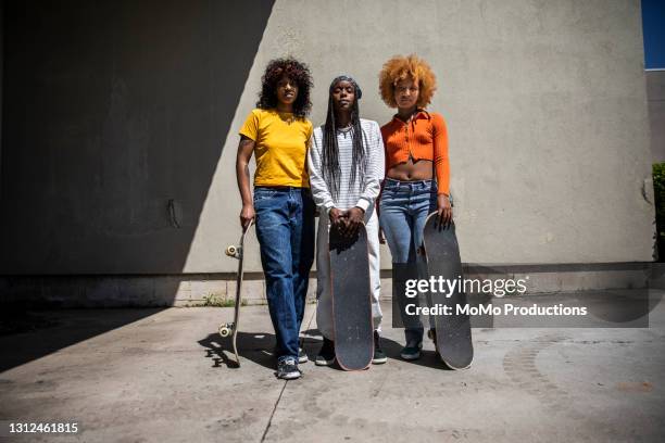 portrait of female skateboarders in outdoor industrial environment - bauchfreies oberteil stock-fotos und bilder