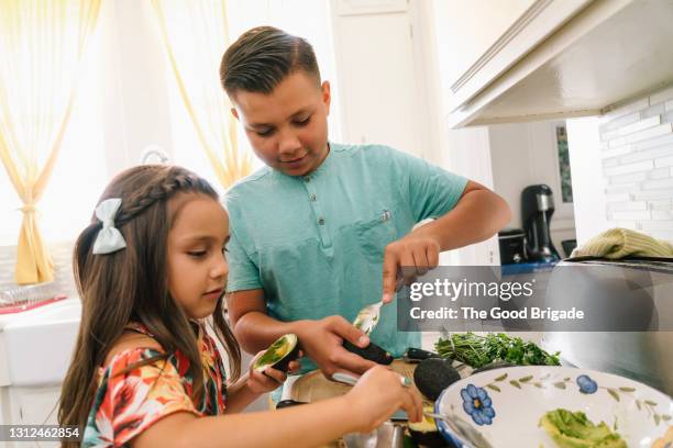 brother and sister making guacamole at kitchen counter - bruder schwester kochen stock-fotos und bilder