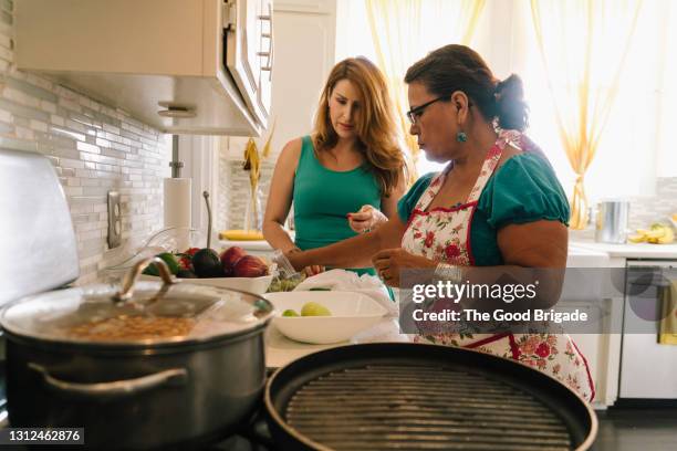 mother and adult daughter preparing a meal in the kitchen - mother daughter cooking stock pictures, royalty-free photos & images