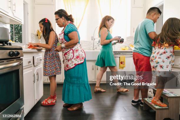 three generations preparing a meal in kitchen at home - traditional home interior stock pictures, royalty-free photos & images