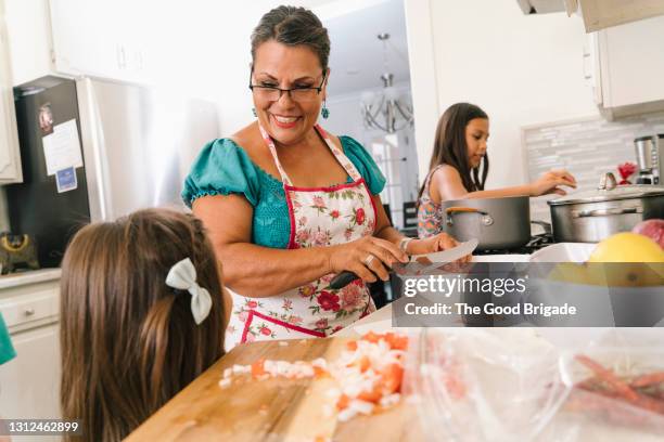 grandmother teaching grandchildren to cook - latino family stock-fotos und bilder