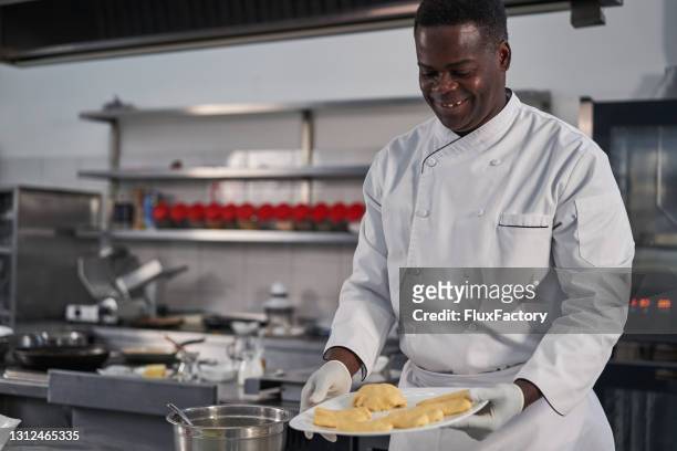 orgulloso jefe jamaiquino sosteniendo el plato con masa amasada - jamaiquino fotografías e imágenes de stock